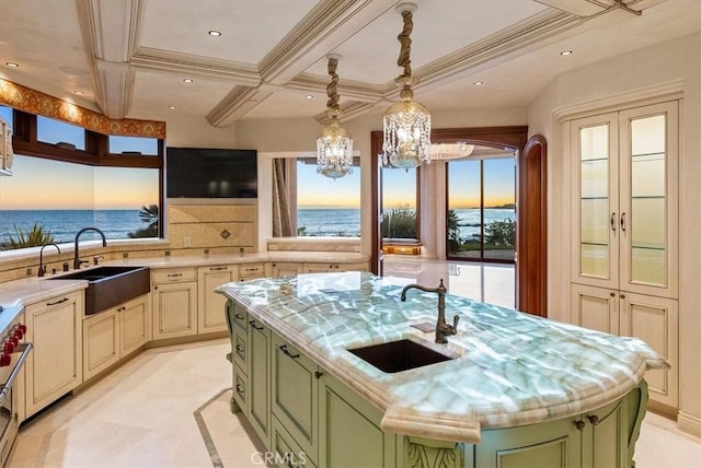 kitchen with light stone counters, a kitchen island with sink, green cabinets, and sink