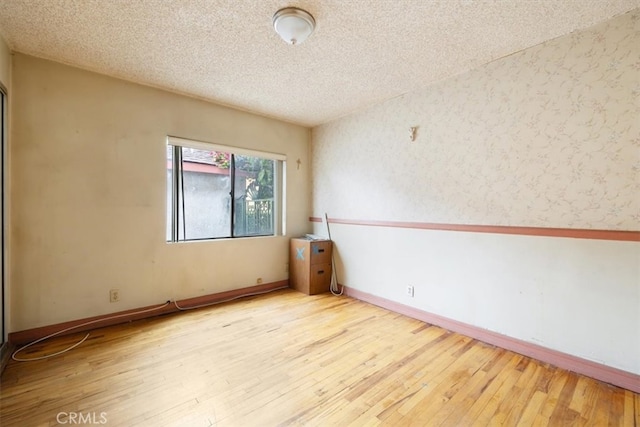 empty room featuring light wood-type flooring and a textured ceiling