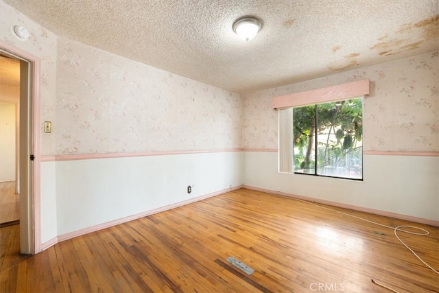 empty room featuring wood-type flooring and a textured ceiling