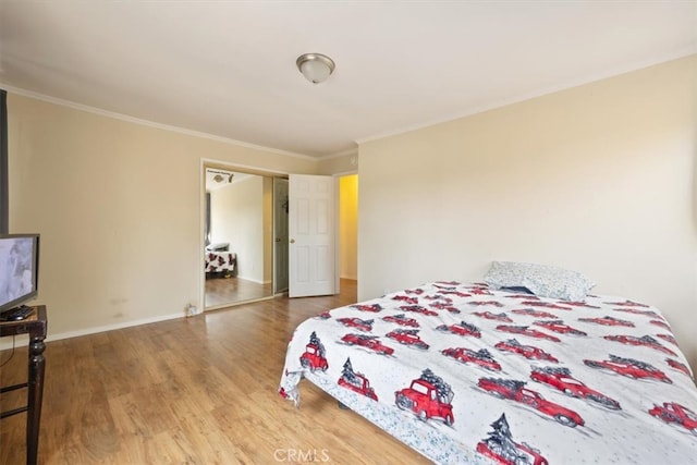 bedroom featuring wood-type flooring, crown molding, and a closet