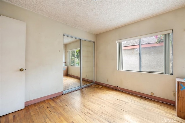 unfurnished bedroom with light hardwood / wood-style flooring, a closet, and a textured ceiling