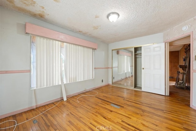 empty room with wood-type flooring and a textured ceiling