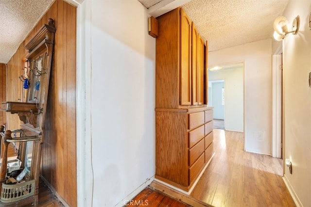 hallway featuring a textured ceiling, wooden walls, and hardwood / wood-style floors