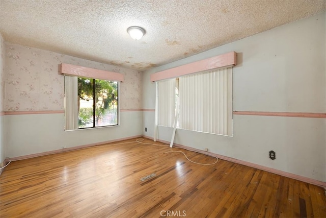 empty room with light hardwood / wood-style floors and a textured ceiling