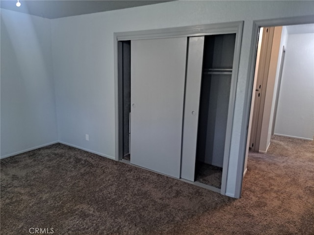 unfurnished bedroom featuring dark carpet and a closet