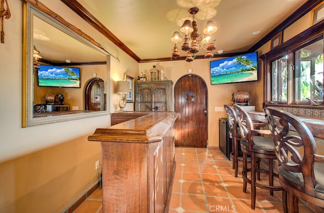 bar with ornamental molding, light tile patterned flooring, and a chandelier