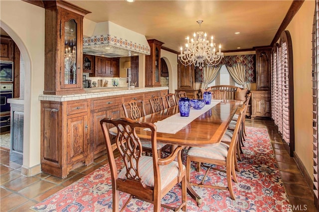 tiled dining room featuring a notable chandelier and ornamental molding