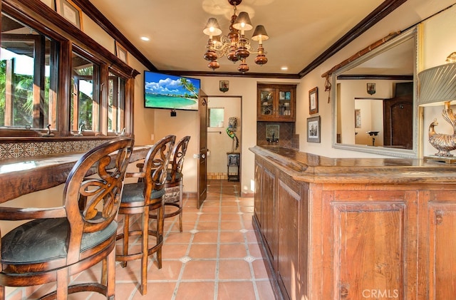 bar featuring a notable chandelier, crown molding, and light tile patterned floors