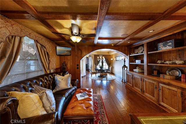 living room with ceiling fan with notable chandelier, hardwood / wood-style floors, coffered ceiling, and a healthy amount of sunlight