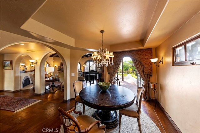 dining area with an inviting chandelier, a tray ceiling, dark hardwood / wood-style floors, and a textured ceiling