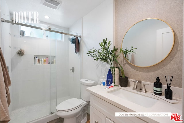 bathroom with an enclosed shower, vanity, and toilet