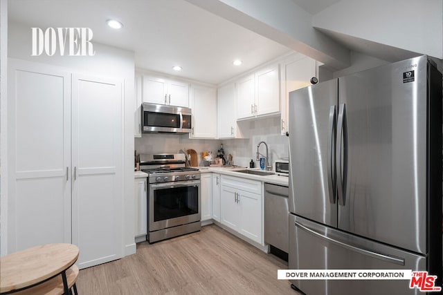 kitchen featuring appliances with stainless steel finishes, light hardwood / wood-style floors, white cabinetry, backsplash, and sink