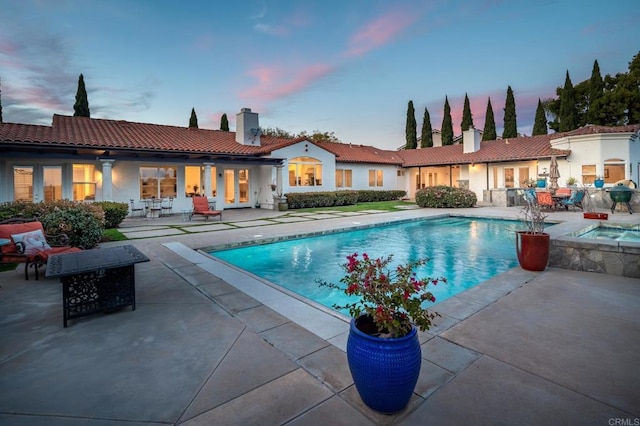 pool at dusk featuring a patio