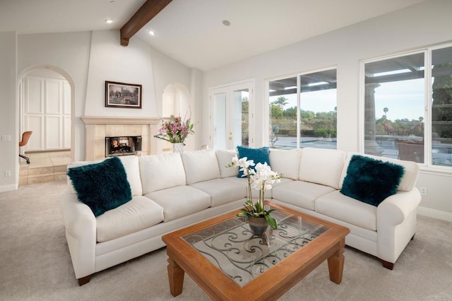 carpeted living room featuring a tiled fireplace and lofted ceiling with beams