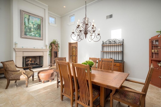 dining area featuring a towering ceiling, a notable chandelier, and crown molding