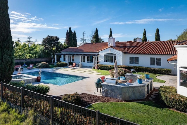 rear view of property with exterior kitchen, a bar, a swimming pool with hot tub, and a patio area