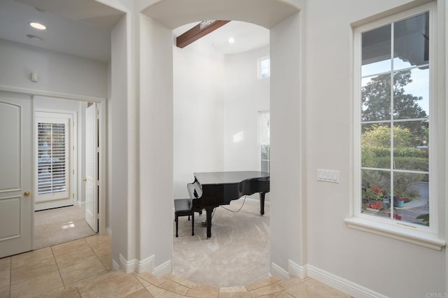 corridor with light tile patterned floors and beamed ceiling