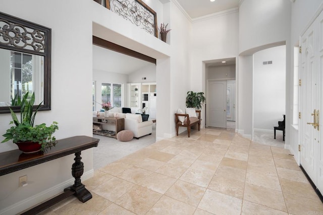 carpeted foyer featuring a high ceiling and ornamental molding