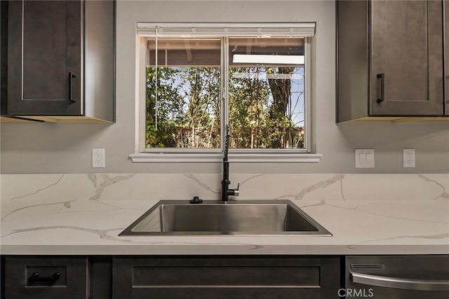 kitchen featuring light stone counters, dark brown cabinets, and stainless steel dishwasher