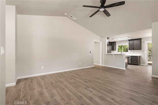 unfurnished living room featuring hardwood / wood-style flooring, ceiling fan, and vaulted ceiling