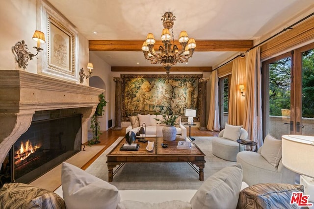 living room with a high end fireplace, light hardwood / wood-style floors, a chandelier, and beamed ceiling