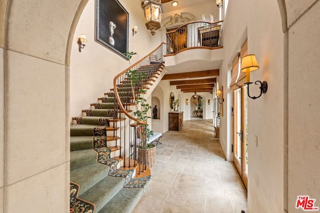 entrance foyer featuring beam ceiling and a towering ceiling