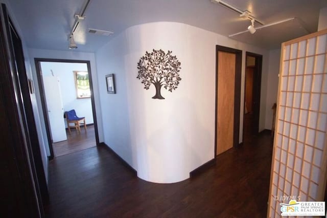 corridor with rail lighting and dark hardwood / wood-style floors