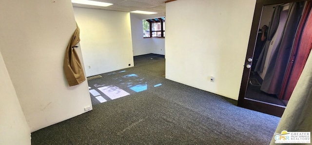 carpeted spare room featuring a paneled ceiling