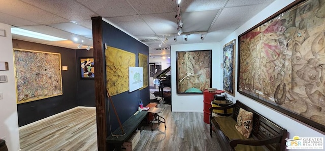 hall featuring a drop ceiling, hardwood / wood-style floors, and track lighting