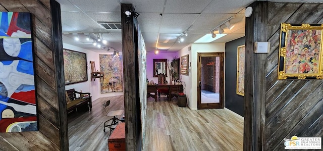 corridor with hardwood / wood-style floors and rail lighting