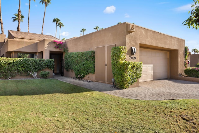 pueblo-style house featuring a garage and a front lawn