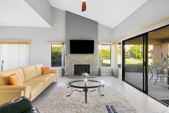 living room with high vaulted ceiling, ceiling fan, and a tiled fireplace