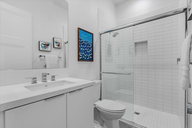 bathroom featuring vanity, an enclosed shower, and toilet