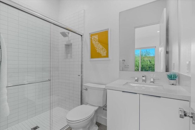 bathroom featuring vanity, toilet, and a shower with shower door