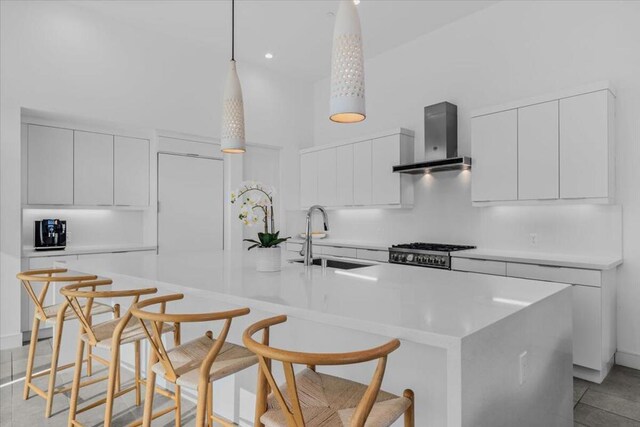 kitchen with white cabinets, wall chimney exhaust hood, sink, and a breakfast bar area