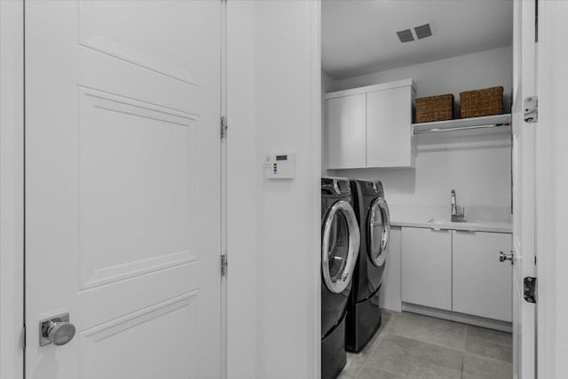 clothes washing area with cabinets, light tile patterned floors, sink, and washing machine and clothes dryer