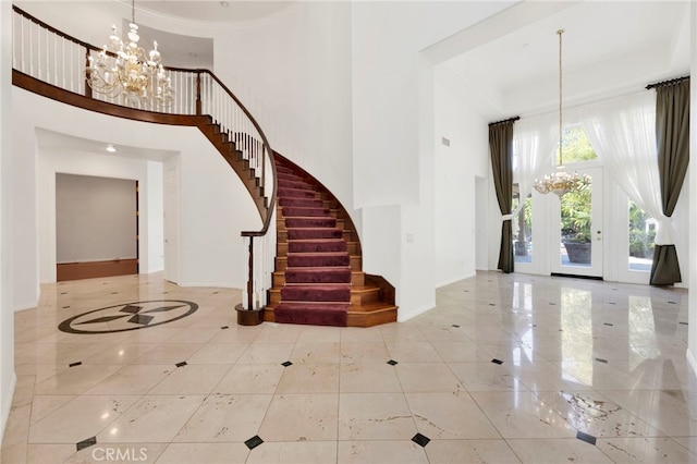 foyer entrance featuring ornamental molding, a high ceiling, and a chandelier