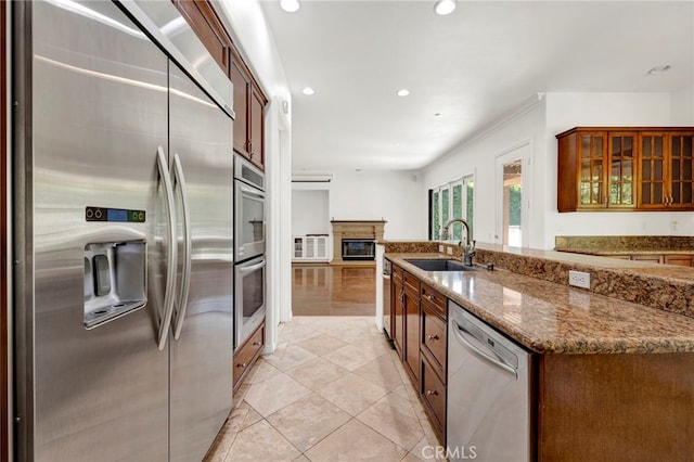 kitchen featuring stainless steel appliances, light tile patterned floors, stone counters, and sink