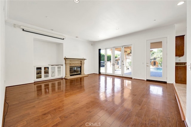 unfurnished living room with wood-type flooring, crown molding, and french doors