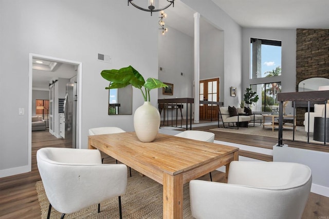 dining space featuring a chandelier, high vaulted ceiling, and wood-type flooring