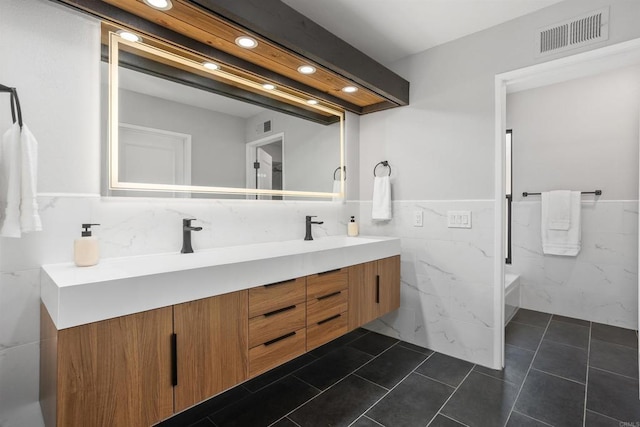 bathroom featuring tile patterned flooring, vanity, and tile walls