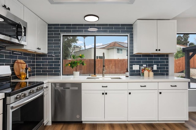 kitchen with white cabinetry, sink, stainless steel appliances, dark hardwood / wood-style flooring, and decorative backsplash