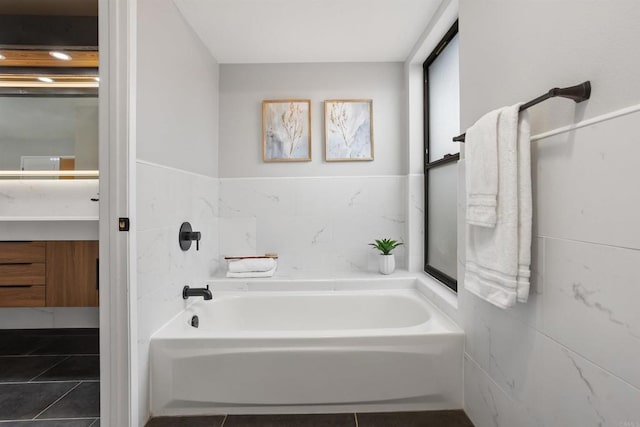 bathroom featuring tile patterned floors, a bathing tub, and tile walls