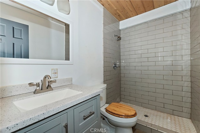 bathroom with tiled shower, wooden ceiling, vanity, and toilet