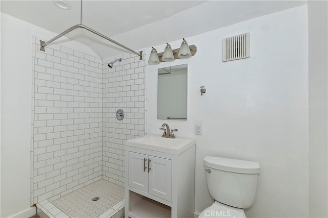 bathroom with a tile shower, vanity, and toilet