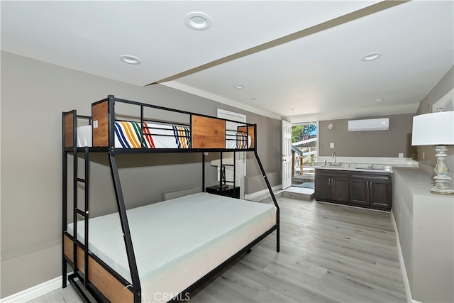 bedroom featuring light hardwood / wood-style flooring and a wall unit AC