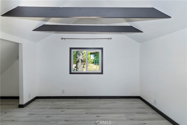 spare room with vaulted ceiling with beams and light hardwood / wood-style floors