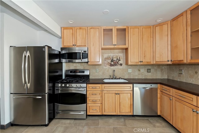 kitchen with light brown cabinetry, stainless steel appliances, sink, and tasteful backsplash