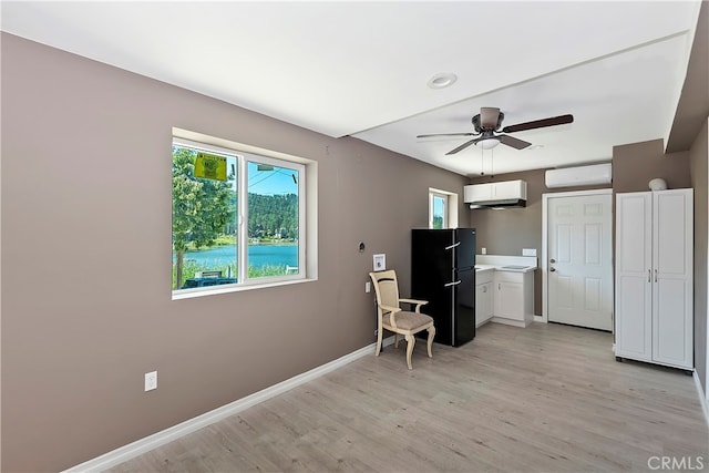 kitchen with white cabinetry, ceiling fan, black fridge, and light hardwood / wood-style flooring