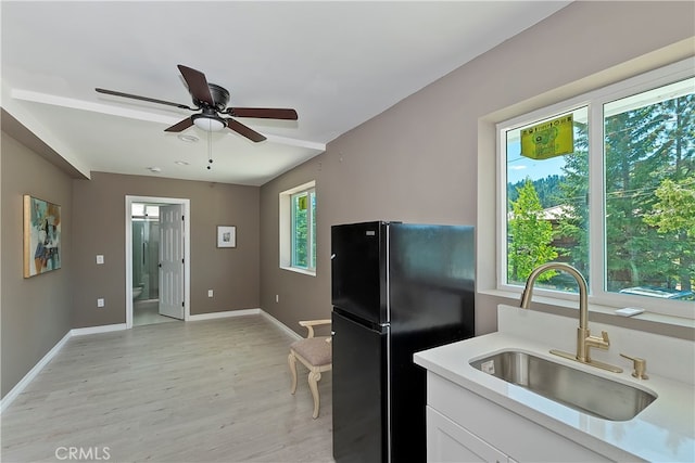 kitchen with black fridge, sink, and a healthy amount of sunlight